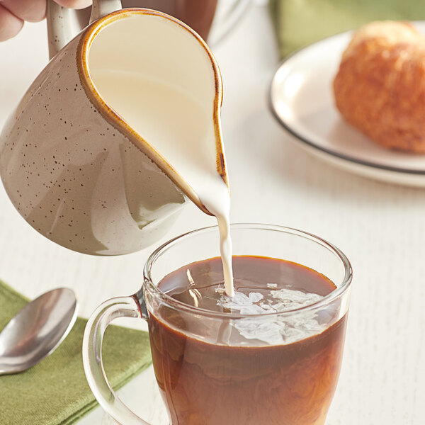 International Delight Half & Half being poured into a glass mug of coffee.