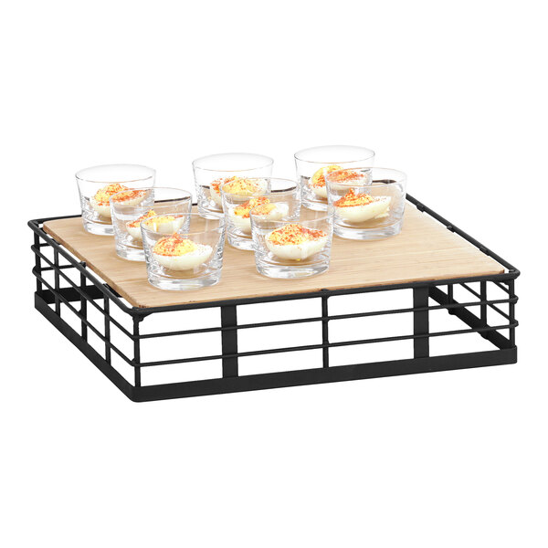 A wood tray with a metal frame holding glasses of food.