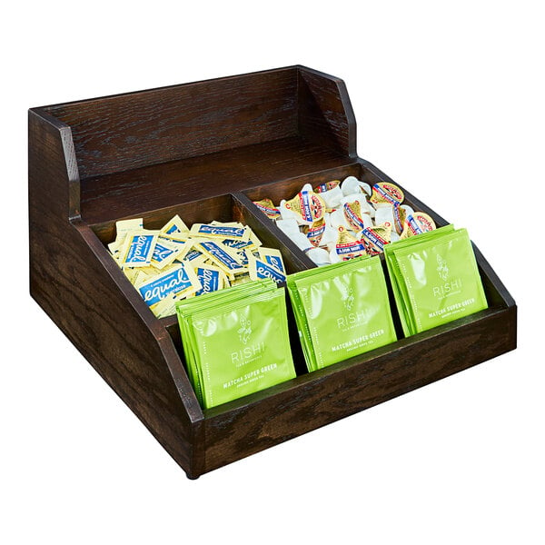 A Cal-Mil dark-stained oak wood condiment organizer on a hotel buffet counter with tea bags inside.