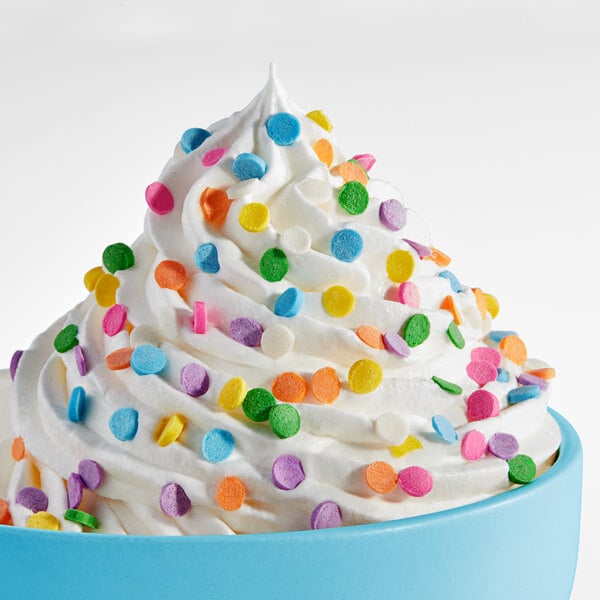 A swirl of white whipped topping decorated with pastel confetti sequin sprinkles in a blue bowl.