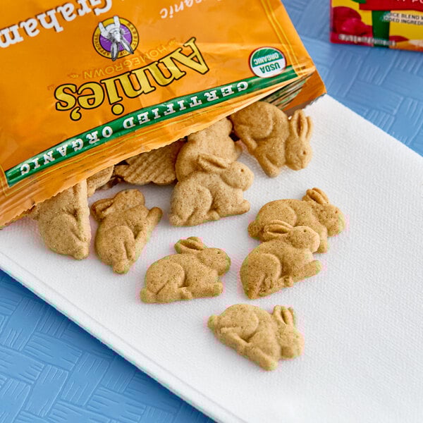 A bag of Annie's Organic Honey Bunny Grahams on a counter next to a bag of carrots.