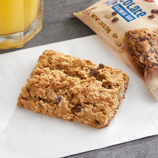 A Betty Crocker chocolate chip oatmeal bar on a napkin next to a glass of orange juice.