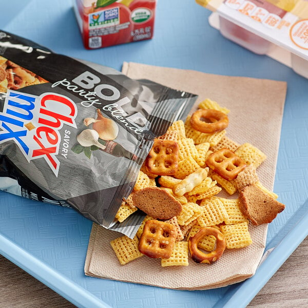 A blue tray with a bag of Chex Mix Bold on top of Chex cereal, pretzels, and crackers.