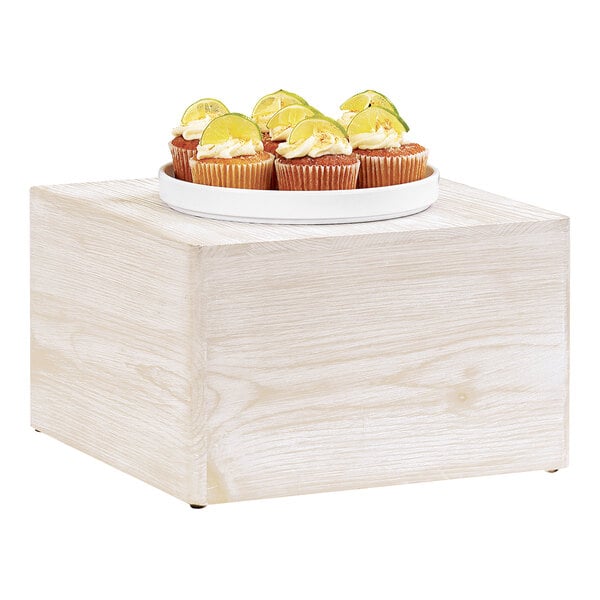 A plate of cupcakes on a white wooden display riser.