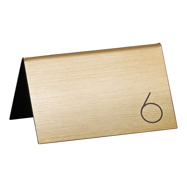 A gold Cal-Mil table tent with a black number 6 on it.