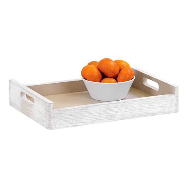 A bowl of oranges on a white-washed pine wood room service tray.
