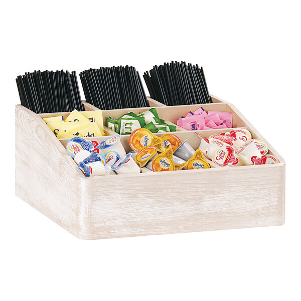 A Cal-Mil white-washed pine wood condiment organizer holding condiments and straws.