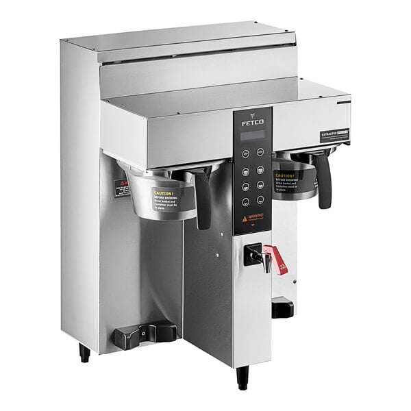 A silver Fetco CBS-1232 Plus Series coffee machine with two metal brew baskets on top.