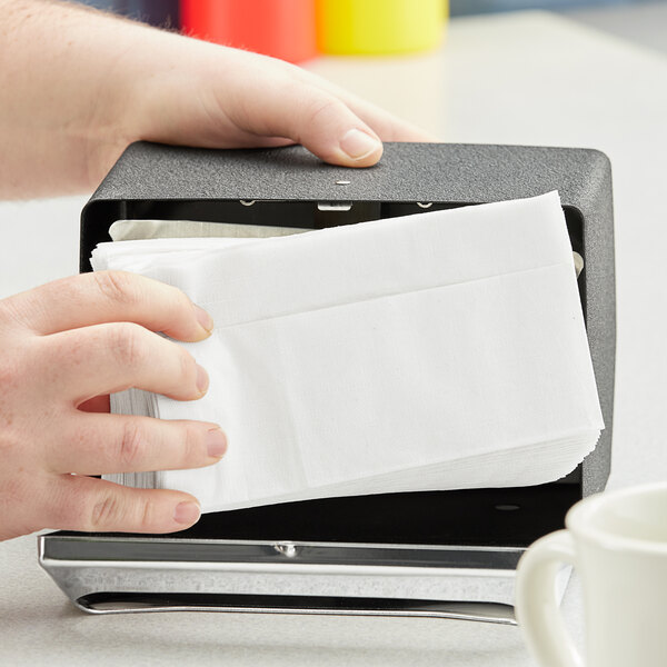 A person holding a white Dixie mini fold napkin in a box.