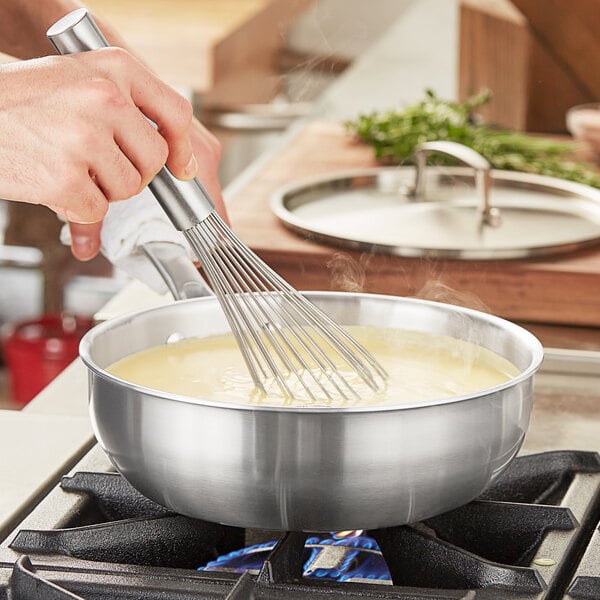 Chef stirring alfredo sauce in a try-ply saucepan