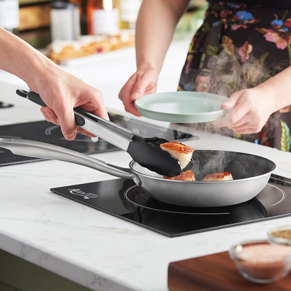 Two people cooking food in a Vigor stainless steel non-stick fry pan.