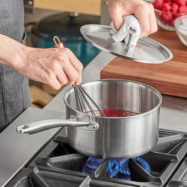 A person whisking red liquid in a Vigor stainless steel sauce pan.