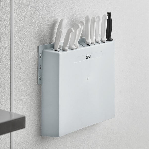 A white plastic wall mount knife rack with knives in it.