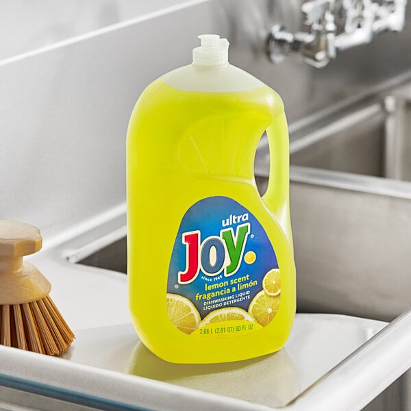 A bottle of Joy lemon scented dish soap on a kitchen sink.