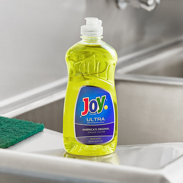 A bottle of JoySuds Joy Ultra lemon scented dishwashing liquid on a counter in a professional kitchen.