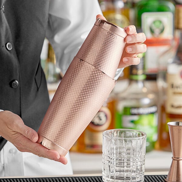 A bartender using a Barfly copper diamond lattice cocktail shaker.