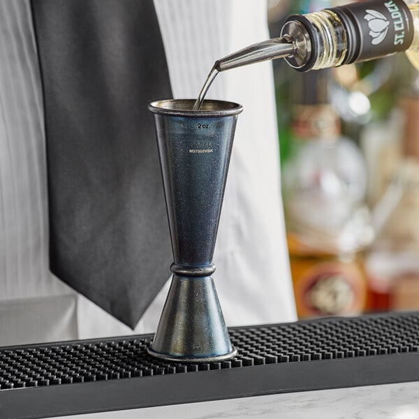 A bartender using a Barfly Japanese style jigger to pour a drink.