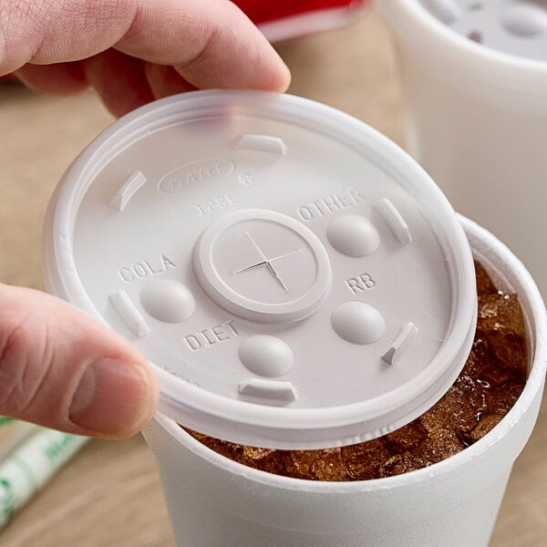 A hand holding a Dart translucent plastic lid on a plastic cup.
