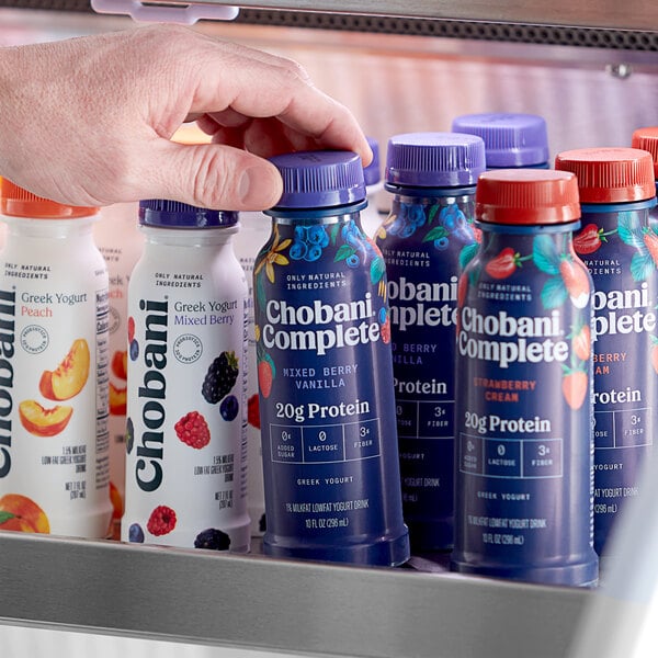 A hand holding a bottle of Chobani Complete Low-Fat Mixed Berry Vanilla Greek Yogurt Drink.