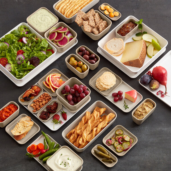 A table with rectangular melamine bowls of food on it.