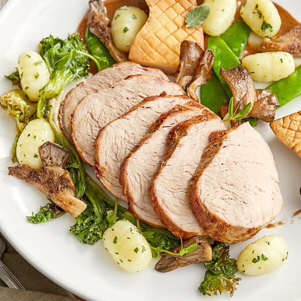 A plate of food with boneless pork tenderloin, potatoes, and green vegetables.