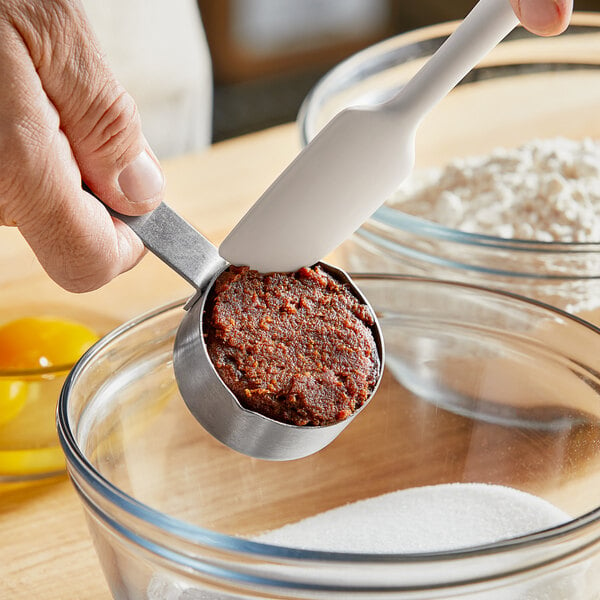 Baker adding date paste to a mixing bowl.