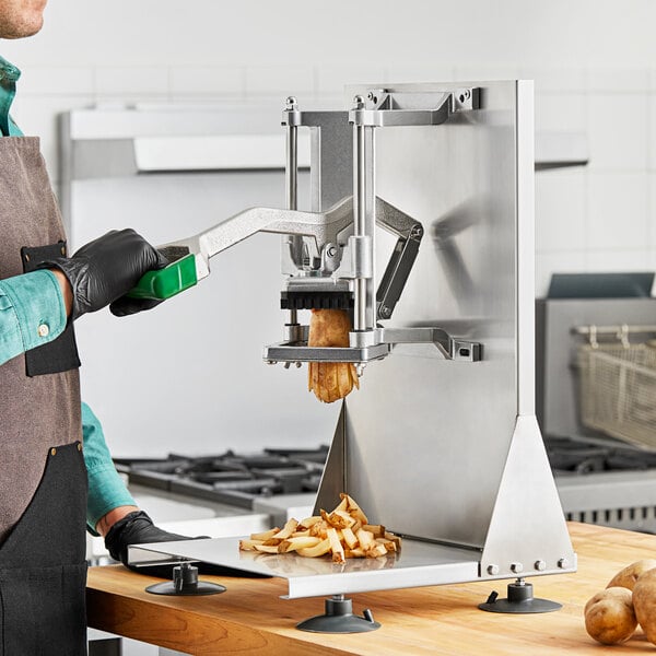 A person in a kitchen using a Garde French fry cutter to cut potatoes.