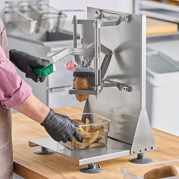 A person in gloves using a Garde Heavy-Duty French Fry Cutter on a countertop to cut potatoes.