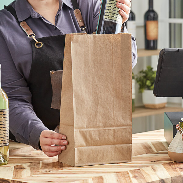 A woman holding a brown Kraft paper bag with a bottle of wine.