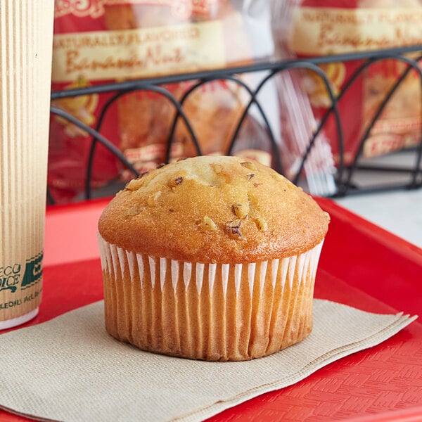 An Otis Spunkmeyer banana nut muffin on a napkin on a red tray.