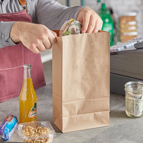 A person holding a ChoiceHD brown paper bag full of food.