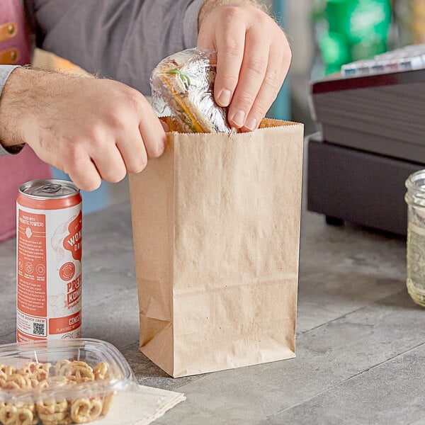 A person putting food in a Choice Natural Kraft paper bag.