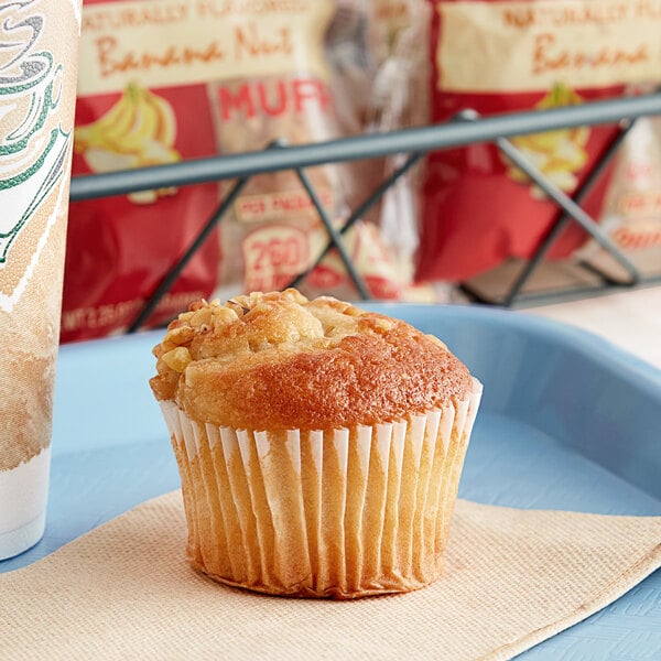 An Otis Spunkmeyer banana nut muffin in a paper wrapper on a tray.