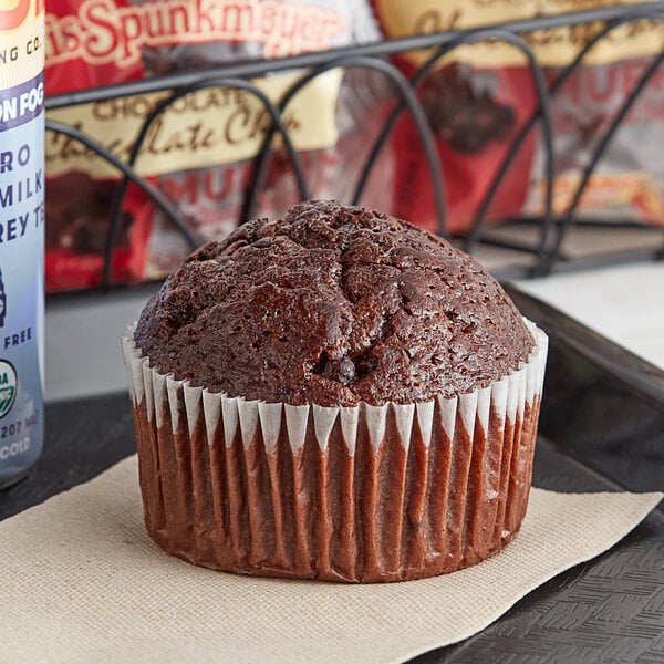 An Otis Spunkmeyer double chocolate muffin in a paper wrapper on a napkin.