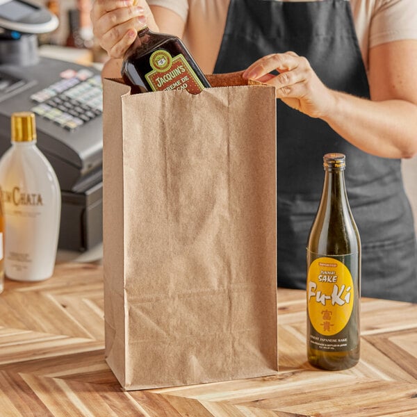 A person's hand putting a bottle of liquor into a ChoiceHD brown paper bag.