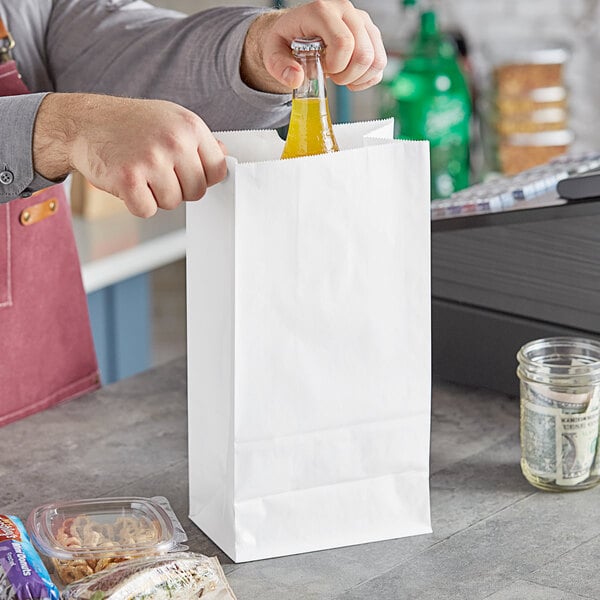 A person pouring yellow liquid into a Choice white paper bag.