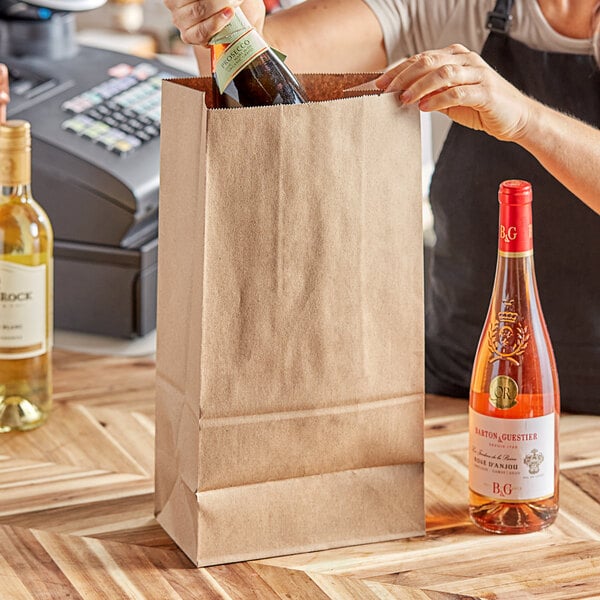 A hand pouring wine into a brown ChoiceHD bag with a black handle.