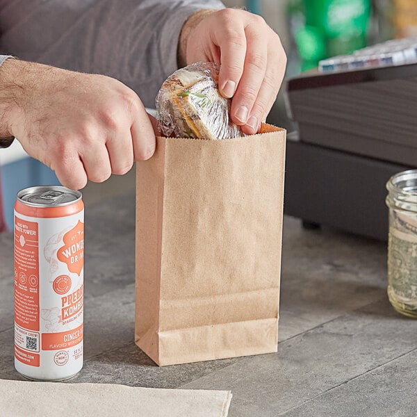 A person putting food in a ChoiceHD natural kraft paper bag.