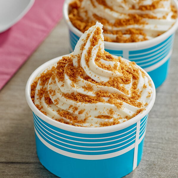 A blue cup of ice cream topped with whipped cream and Lotus Biscoff crumbles.