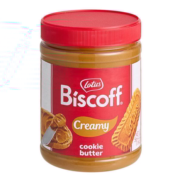A jar of Lotus Biscoff creamy cookie butter on a table with a knife.
