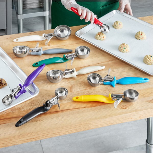 A woman using a blue Choice thumb press disher to scoop ice cream into a silver bowl.
