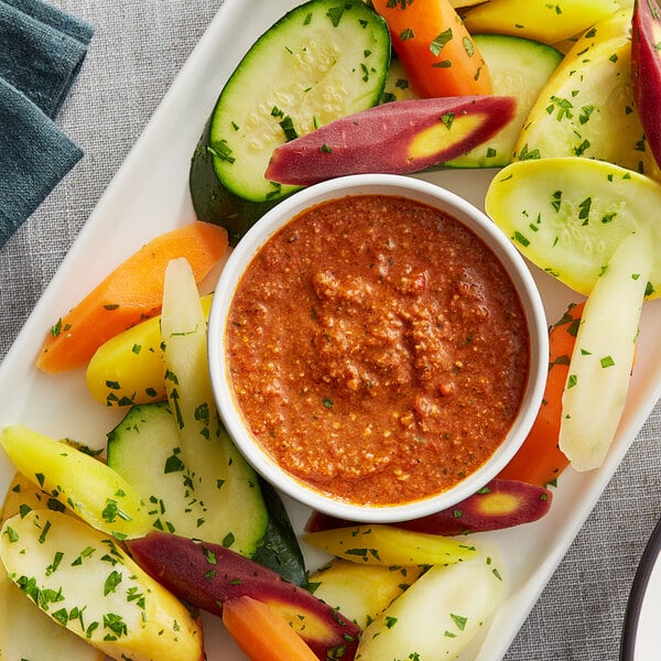 A plate of sliced vegetables with Armanino Romesco sauce on a table.