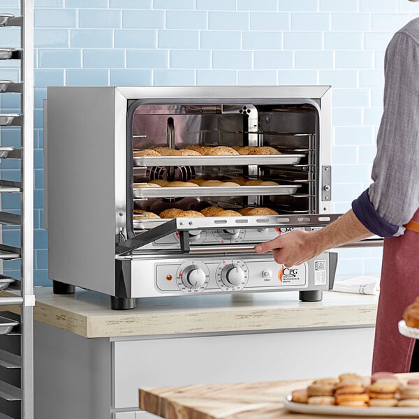 A man using a Cooking Performance Group countertop convection oven.