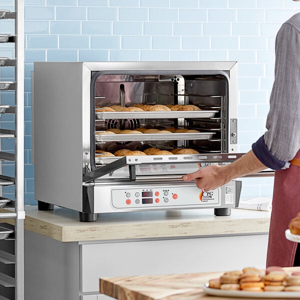 A person opening a Cooking Performance Group countertop convection oven with food in it.