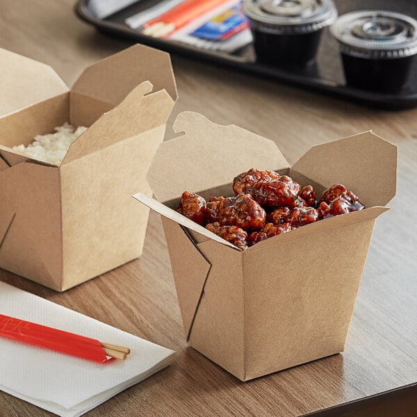 Two Emperor's Select Chinese takeout containers with food in them on a table.