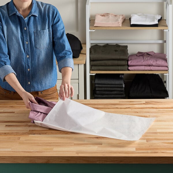 A person putting white Vela layflat shipping bags into a drawer.
