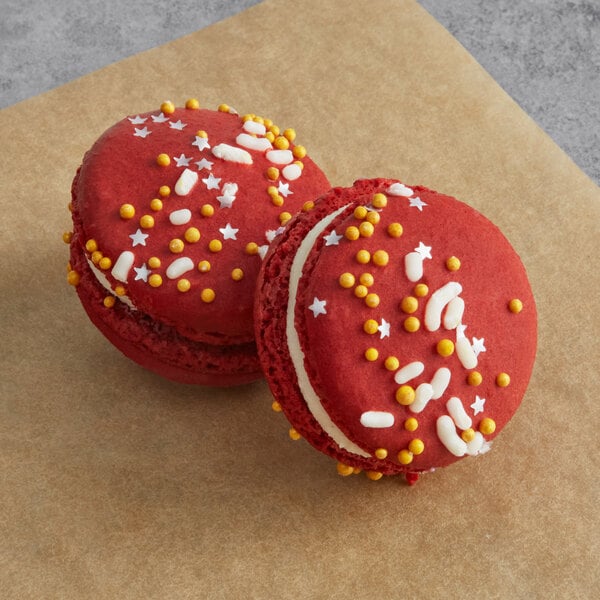 Two blue macarons with white and yellow sprinkles on a table in a bakery display.