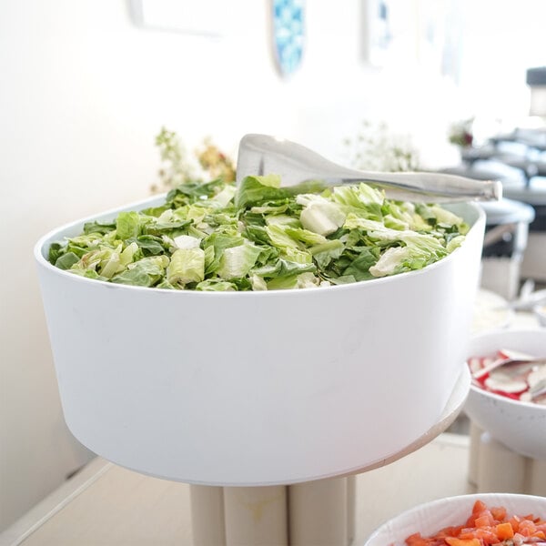 A white Cal-Mil bowl with a raised rim holding salad on a table in a salad bar.