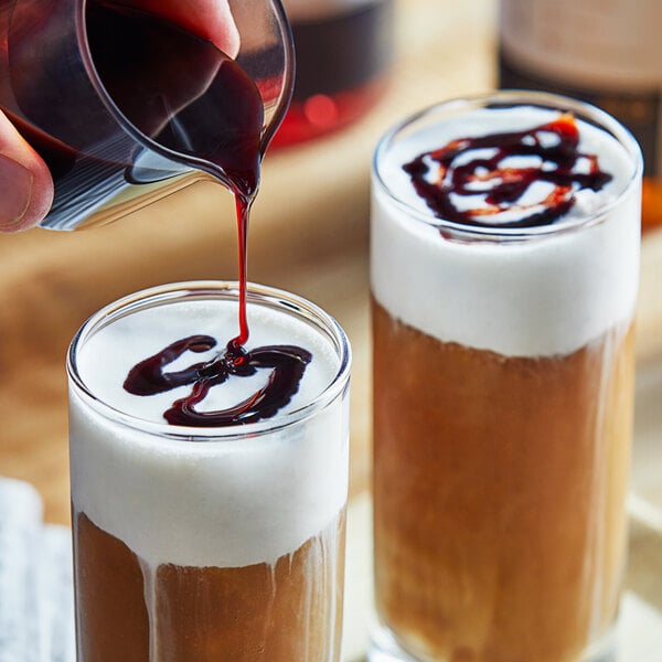 A person pouring Date Lady Organic Date Syrup into a glass of liquid.