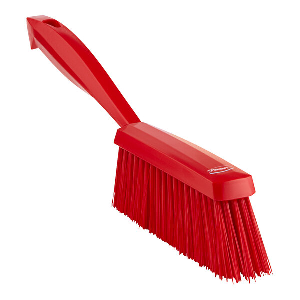 A red Vikan hand brush with a long handle.